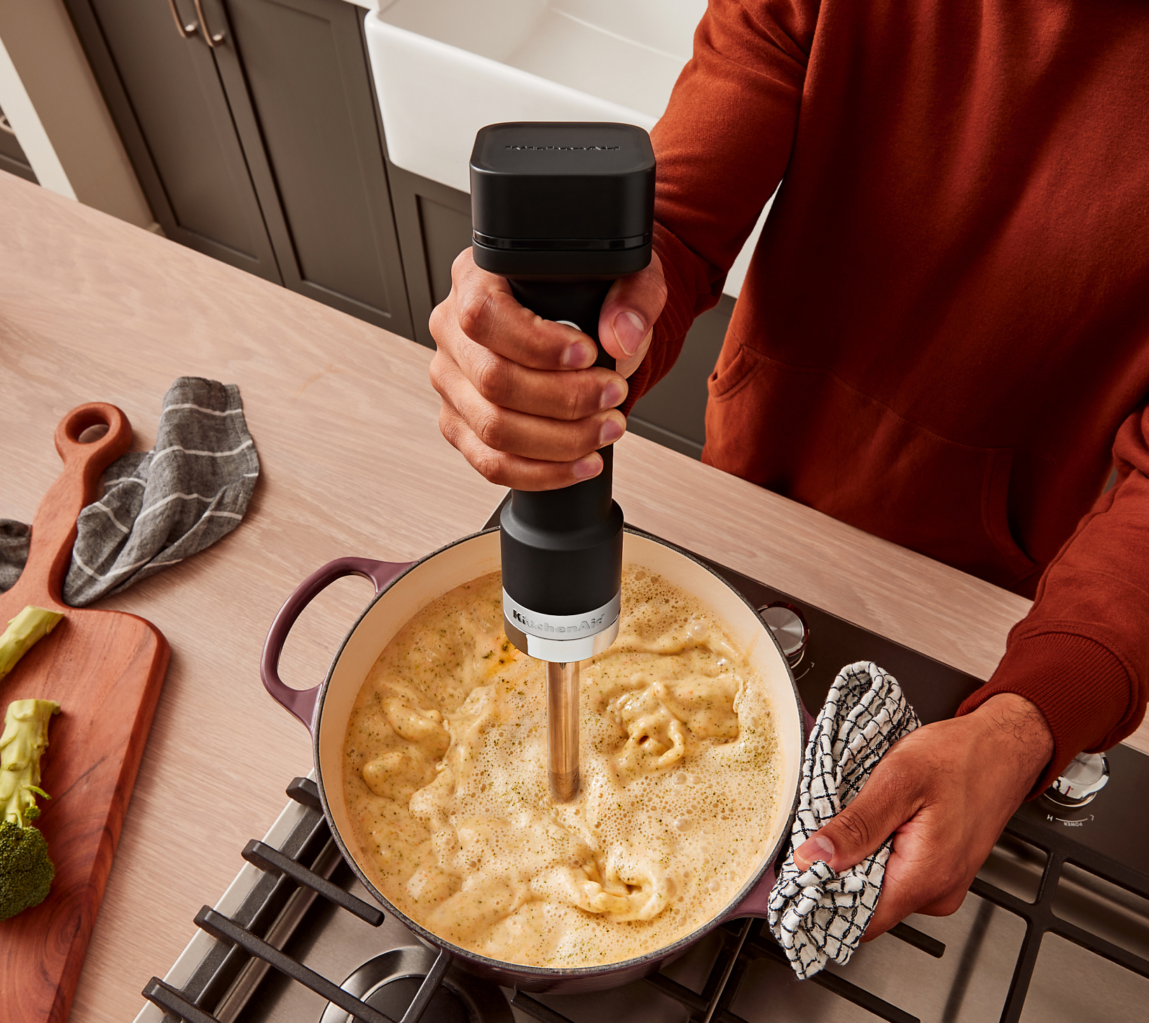 A person using the KitchenAid Go™ Cordless Hand Blender to blend soup.