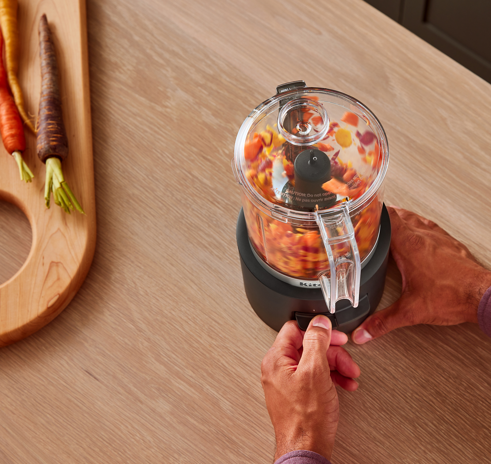 A person using the KitchenAid Go™ Cordless Food Chopper to chop orange, purple and yellow vegetables.