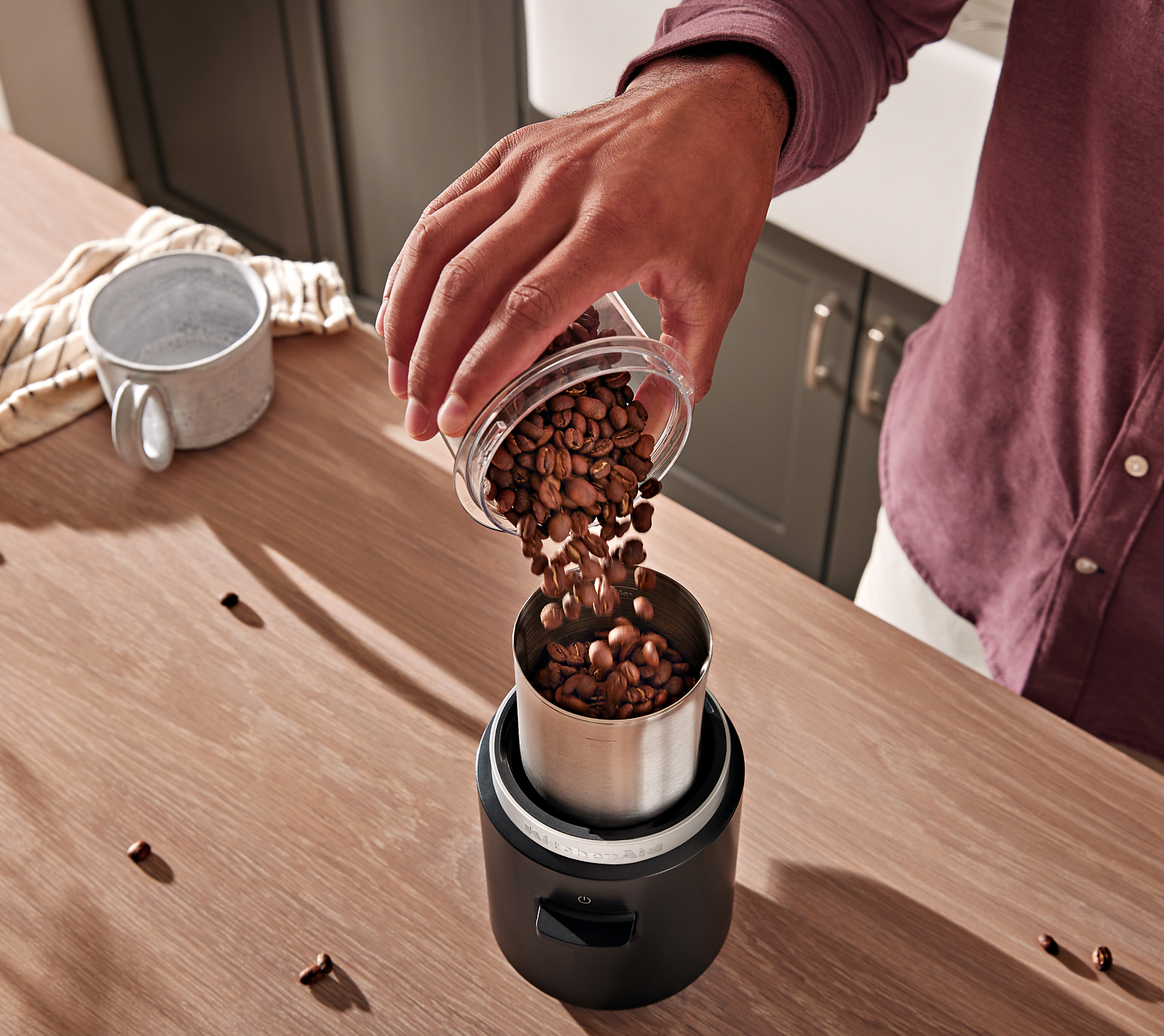Une personne versant des grains de café dans le moulin à lame sans fil KitchenAid Go™.