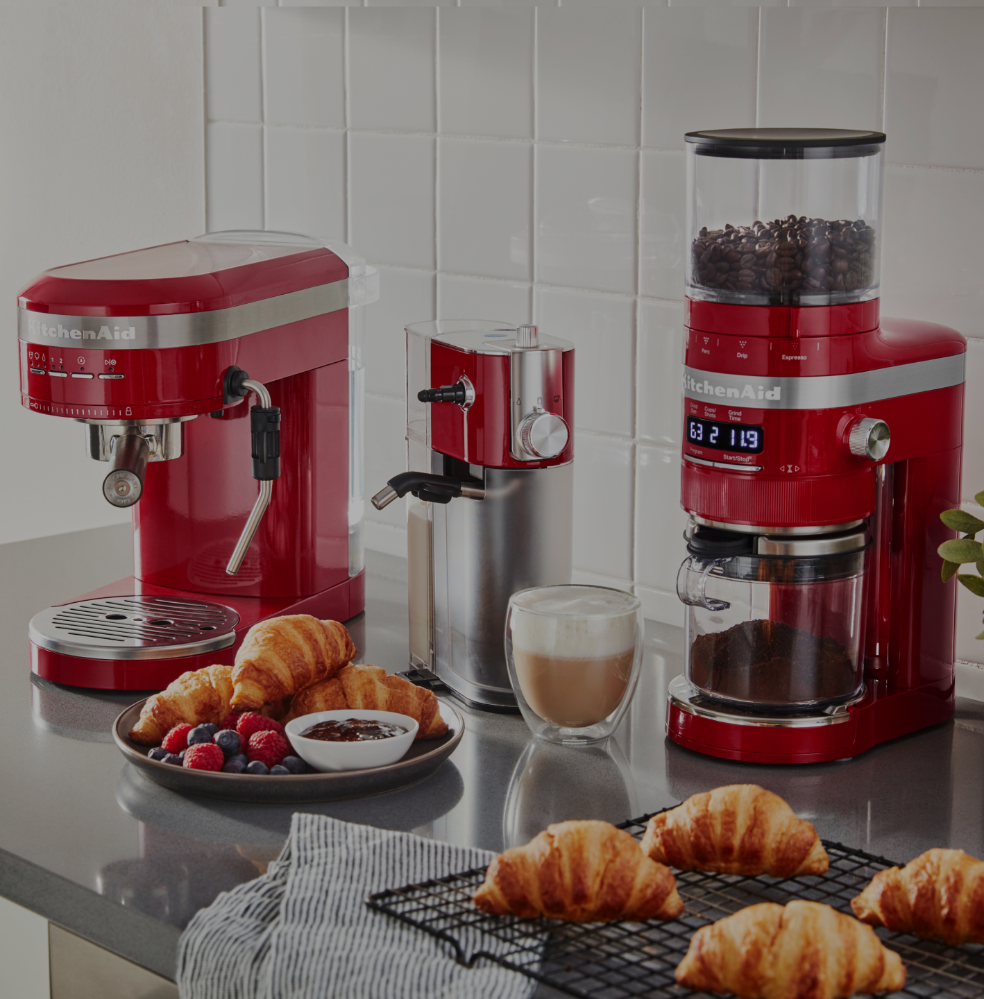 A close-up of a kitchen countertop with two red KitchenAid® countertop appliances.