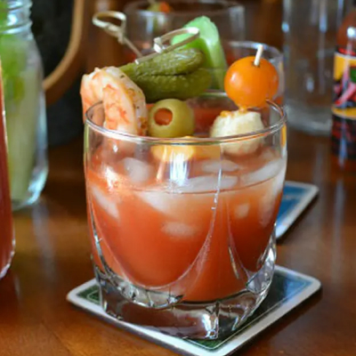 A non-alcoholic Bloody Mary with a shrimp, pickle and olive garnish.