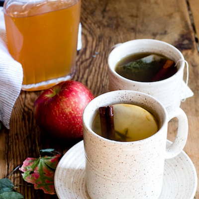 Two mugs of hot apple cinnamon shrub tea.