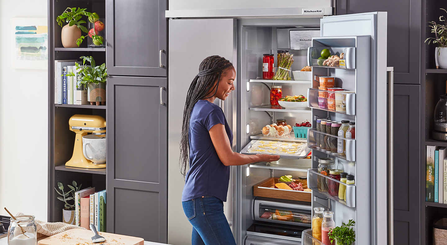 Woman placing food inside a KitchenAid® refrigerator