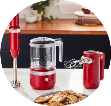 Empire Red KitchenAid® Cordless Immersion Blender, Food Chopper, and Hand Mixer on white countertop.