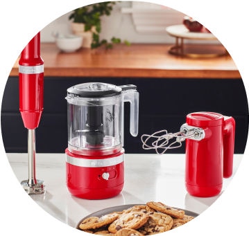 Passion Red KitchenAid® Cordless Immersion Blender, Food Chopper, and Hand Mixer on white countertop.