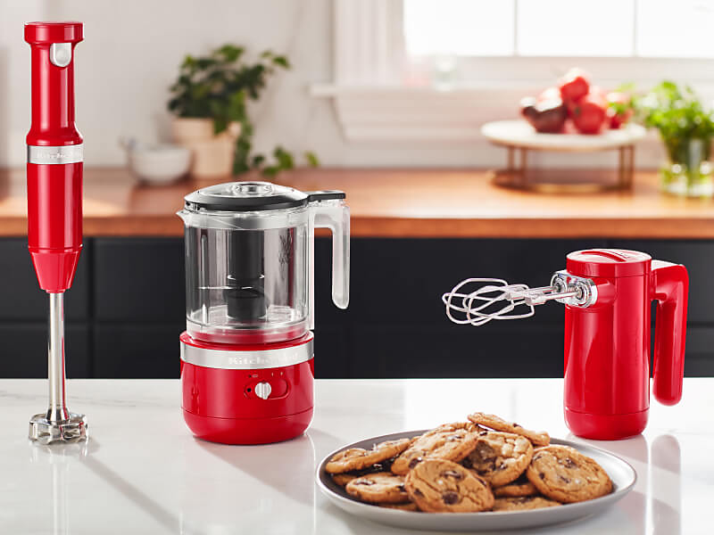 KitchenAid® red cordless hand blender, food chopper and hand mixer on a countertop