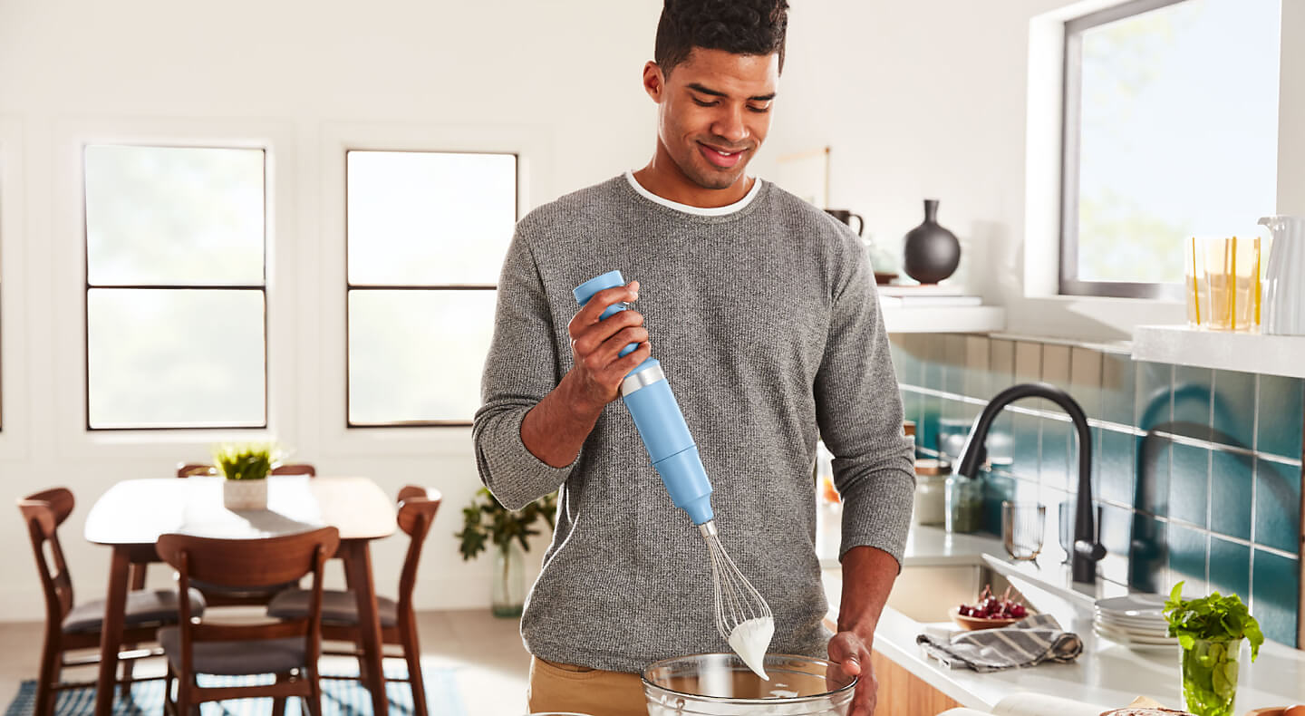 Person using a KitchenAid® cordless hand blender with whisk attachment