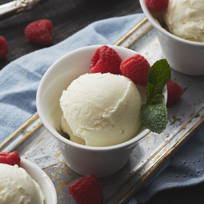 Individual bowls with scoops of vanilla ice cream and fresh raspberries on a table
