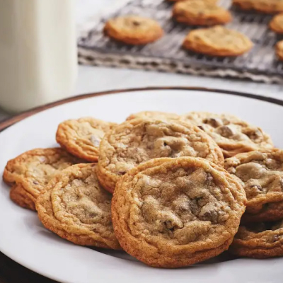 Baked chocolate chip cookies on a plate next to a cooling rack