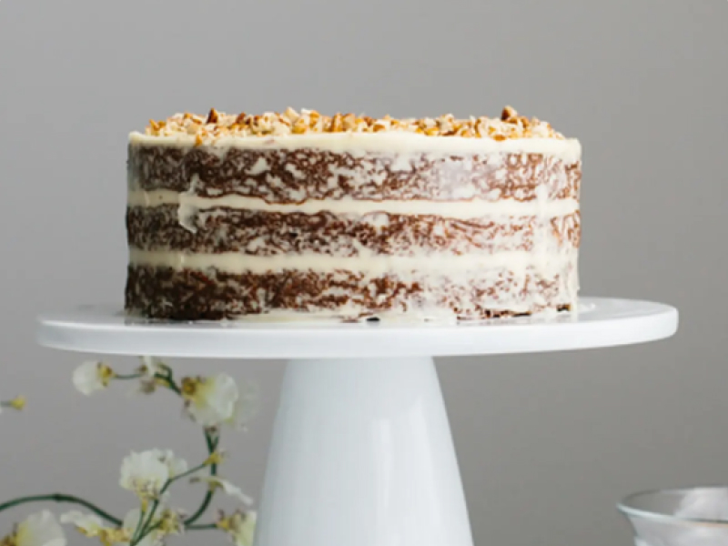 Triple layer gluten-free carrot cake on white cake stand