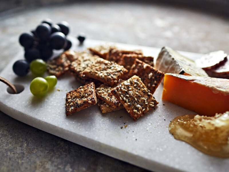 Crackers on cheese board with grapes and cheese