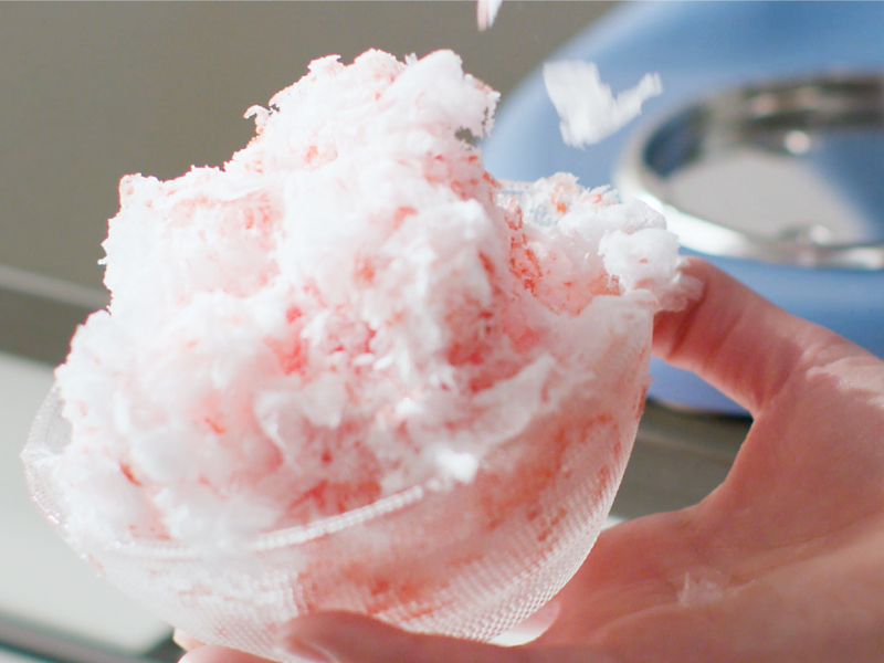 Fluffy shaved ice in front of a blue KitchenAid® stand mixer.