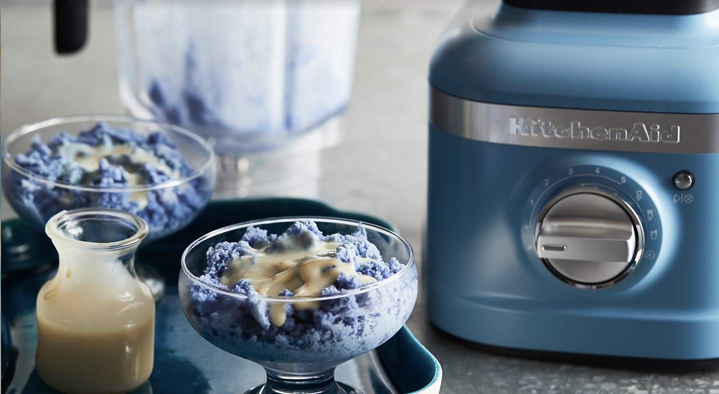 Blue baobing topped with condensed milk next to a KitchenAid® blender.