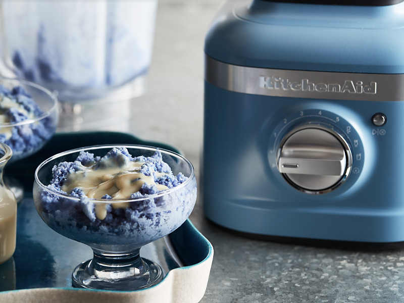 Blue baobing topped with condensed milk next to a KitchenAid® blender.
