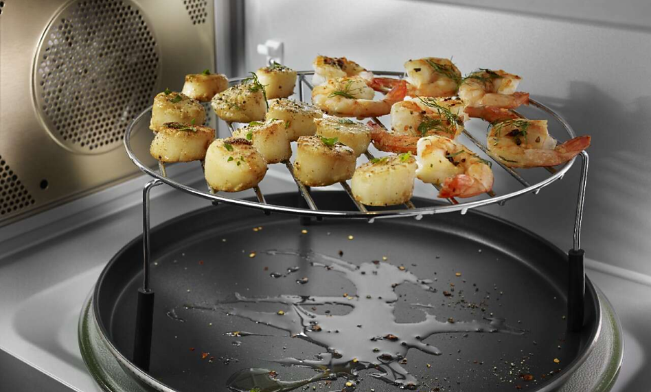 Scallops and shrimp cooking inside a microwave on a raised tray