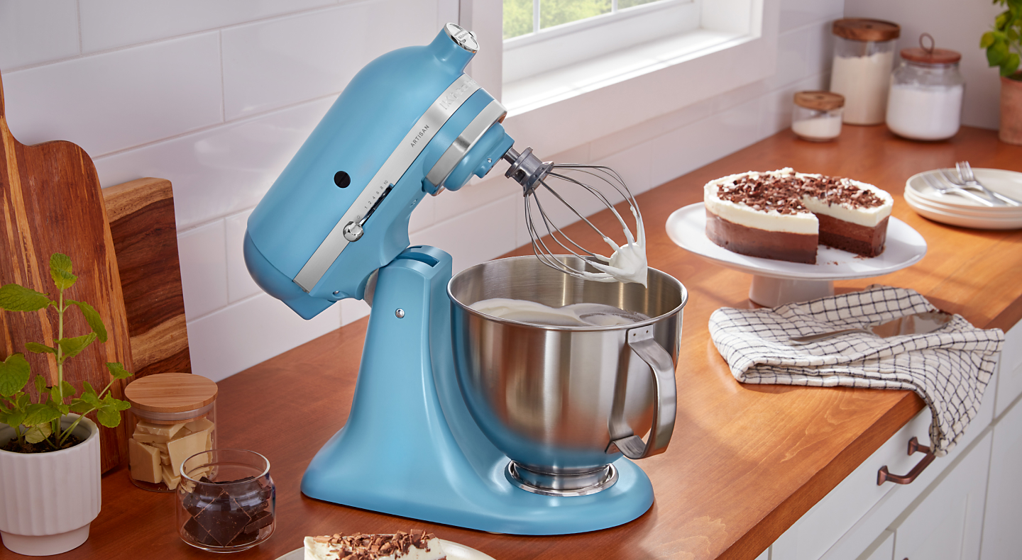 A KitchenAid® stand mixer whipping egg whites into meringue for a pie in a modern kitchen.