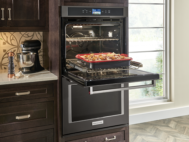 Open KitchenAid® double wall oven with a tray of potatoes on the rack 