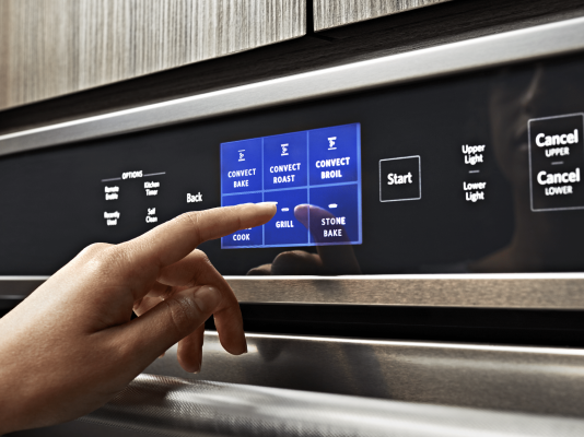 Hand selecting a setting on a KitchenAid® oven control panel