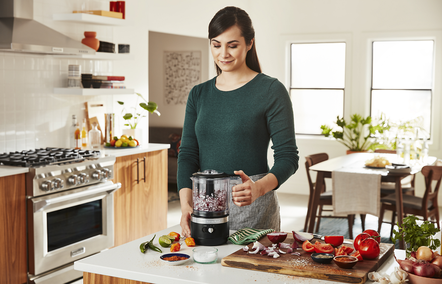 A person chopping vegetables with a KitchenAid® food processor. A person chopping vegetables with a KitchenAid® food processor.