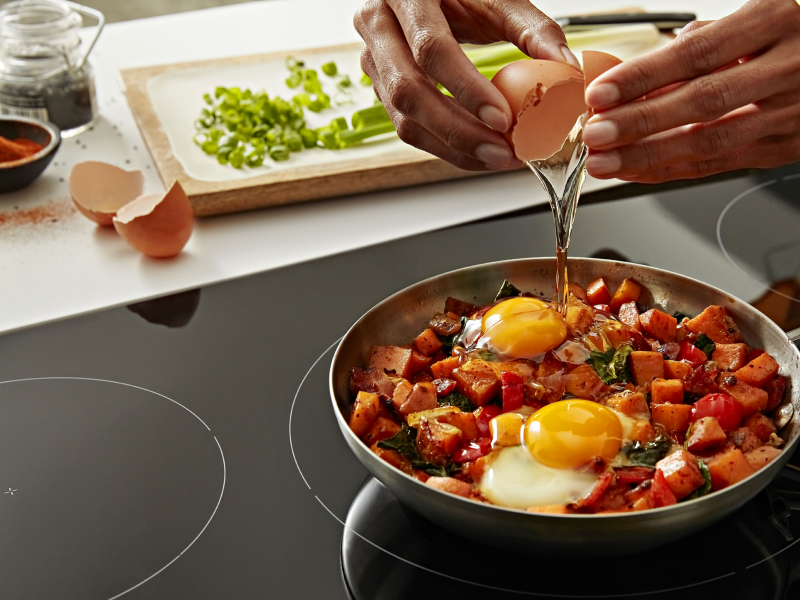 Hands cracking an egg over a pan