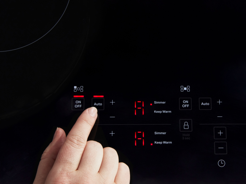 A finger selecting a KitchenAid® induction cooktop feature