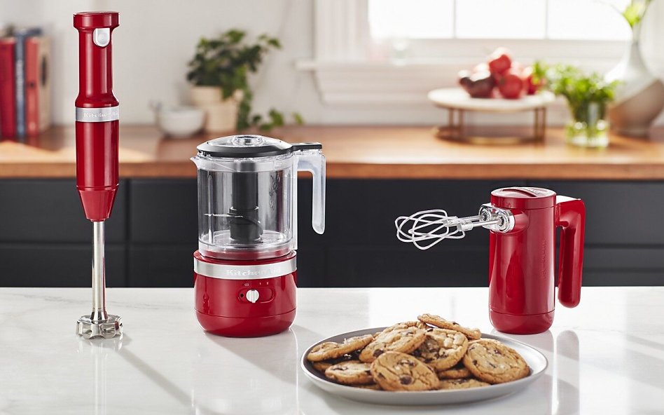Red KitchenAid® cordless collection appliances on counter with cookies Red KitchenAid® cordless collection appliances on counter with cookies