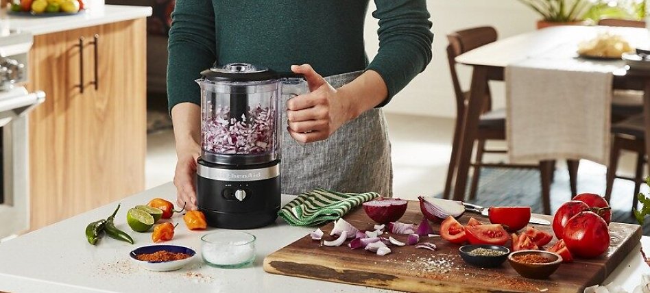 Woman chopping onions with a black cordless food chopper Woman chopping onions with a black cordless food chopper