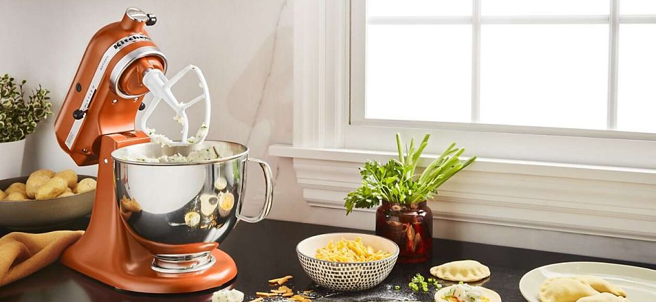 Orange stand mixer on counter with filling for empanadas Orange stand mixer on counter with filling for empanadas