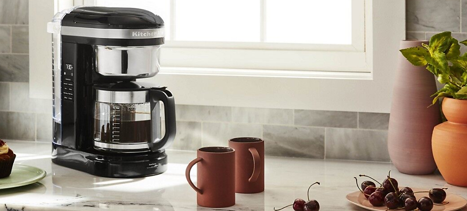 Black auto drip coffee maker with two mugs of coffee