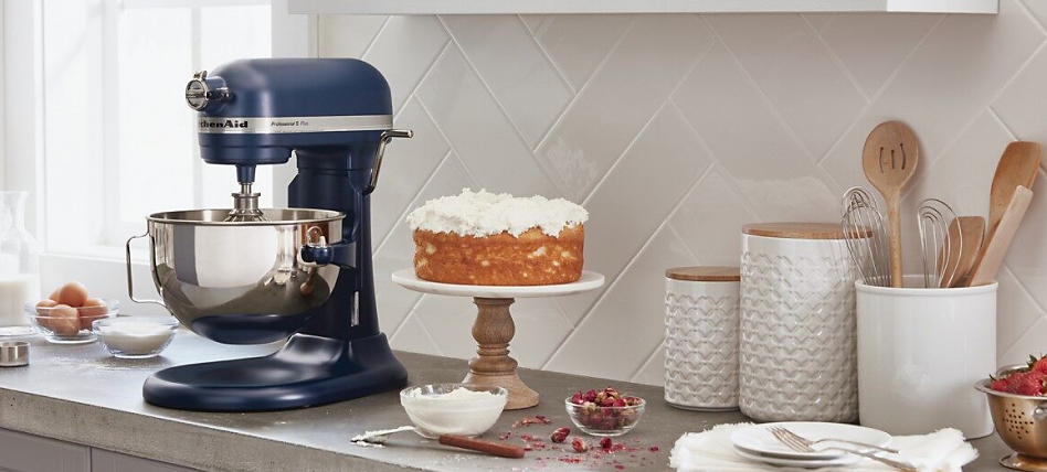 Blue bowl-lift stand mixer on counter next to cake