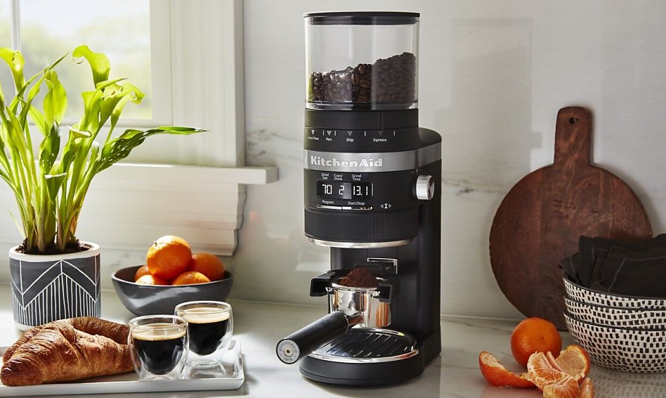 Black burr coffee grinder filling a portafilter on counter with brewed espresso Black burr coffee grinder filling a portafilter on counter with brewed espresso