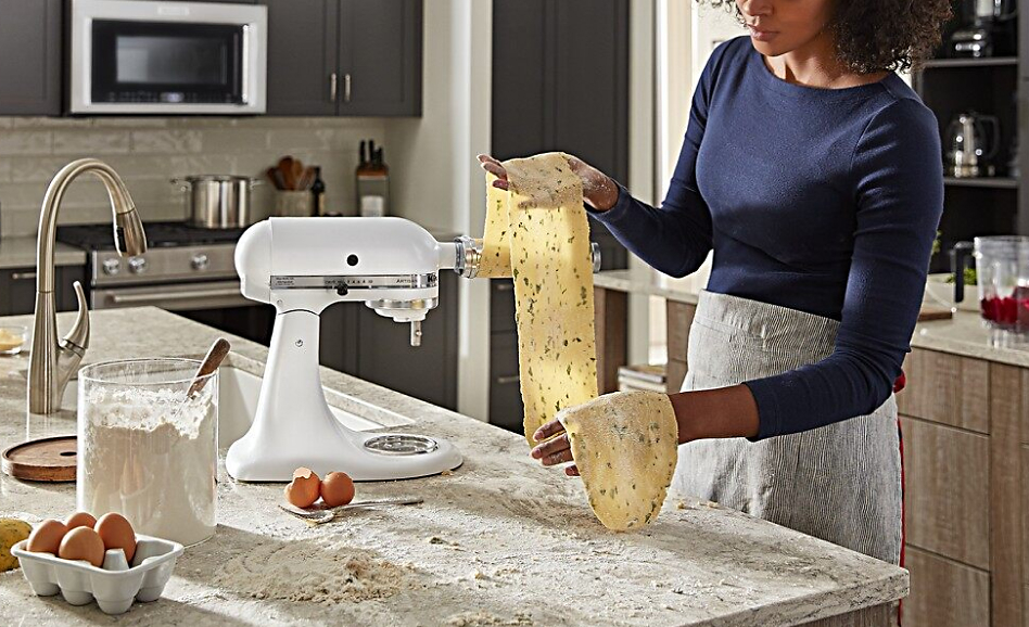 Woman using white stand mixer to roll homemade pasta with an attachment