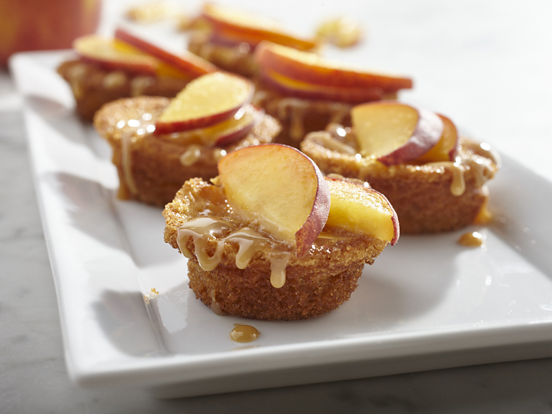 Muffins drizzled with caramel and topped with apple slices.