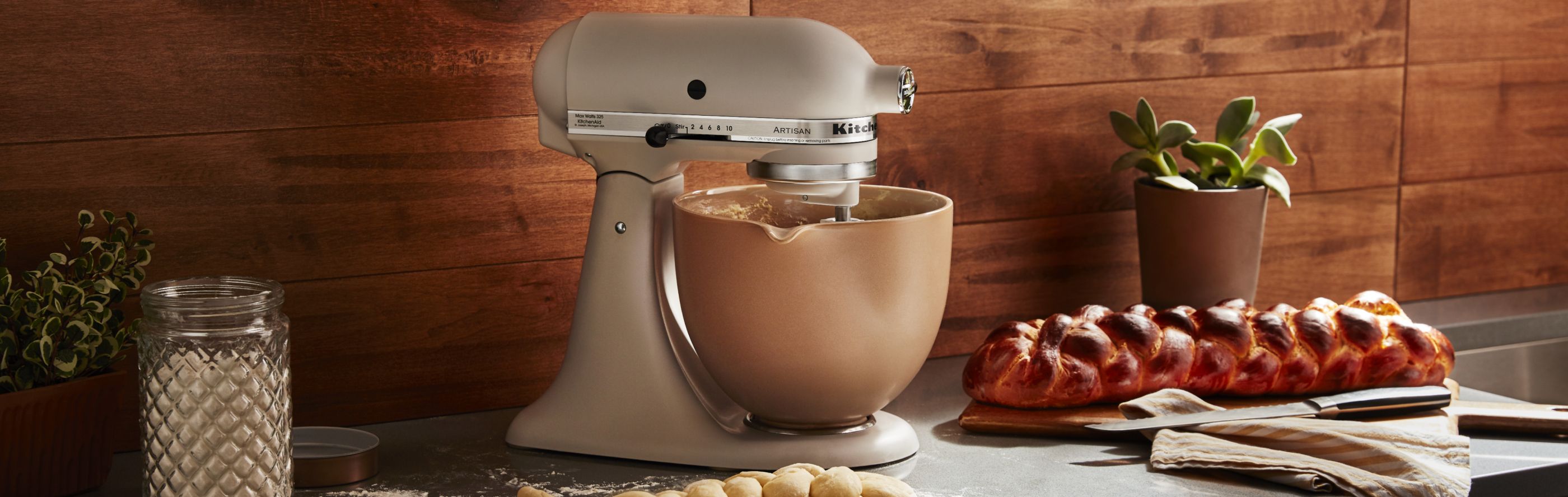 A white KitchenAid® stand mixer next to a loaf of homemade bread.