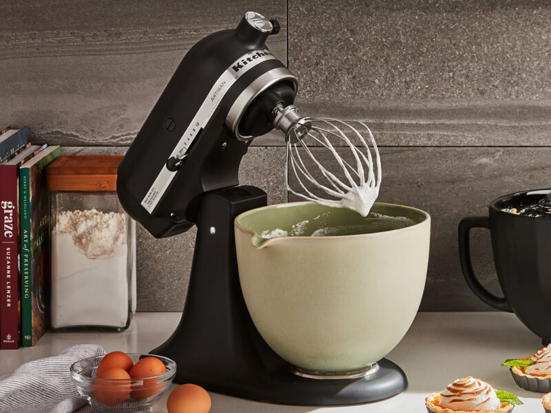 KitchenAid® stand mixer with green ceramic bowl and wire whip on countertop