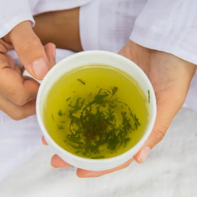A person holding a white tea cup with ground herbs