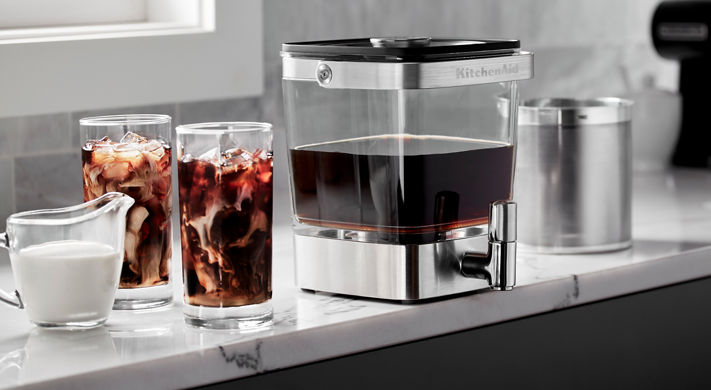 KitchenAid® Cold Brew Coffee Maker next to two glasses of cold brew