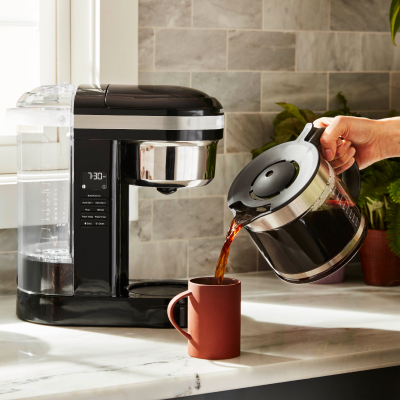 Black KitchenAid® drip coffee maker pouring coffee into a mug