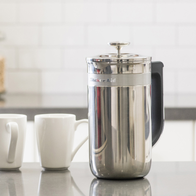 French press coffee maker next to two mugs