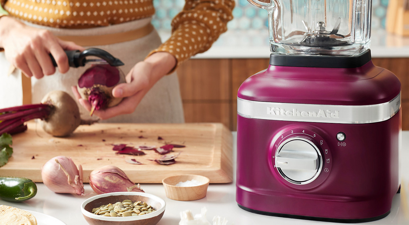 KitchenAid® blender in Beetroot on countertop next to woman preparing beets