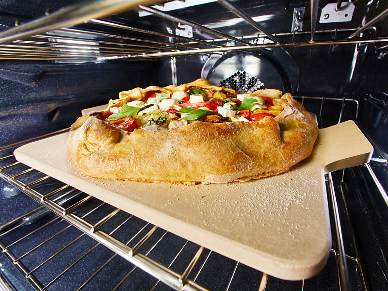 A homemade pizza cooking on the middle rack of an oven