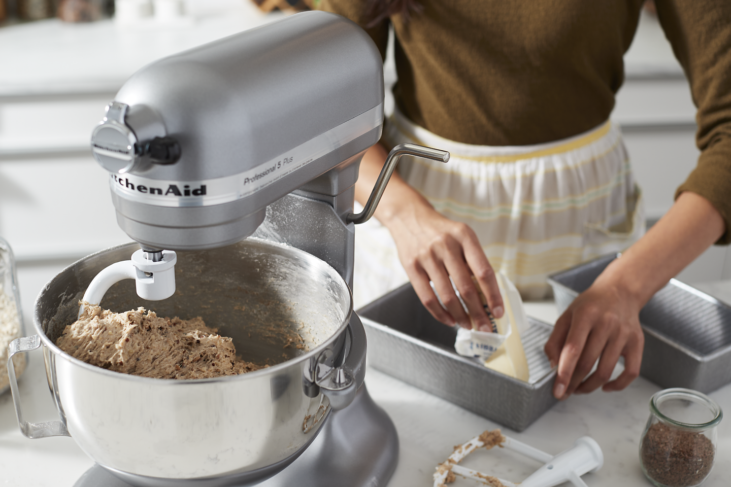 A person using a silver KitchenAid® stand mixer.