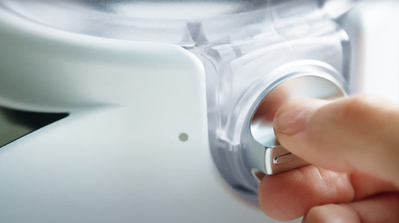A person turning the dial on a KitchenAid® stand mixer attachment.