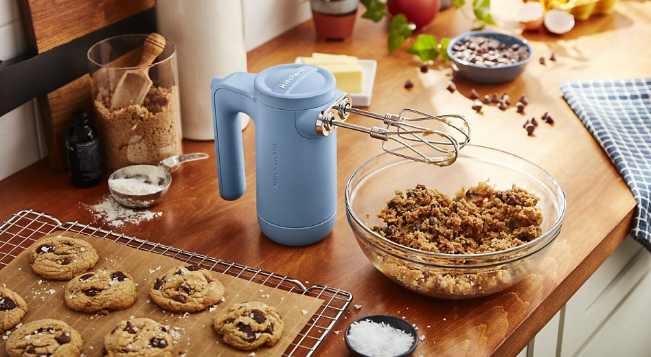KitchenAid® hand mixer with bowl of cookie dough and wire rack with  fresh baked cookies.