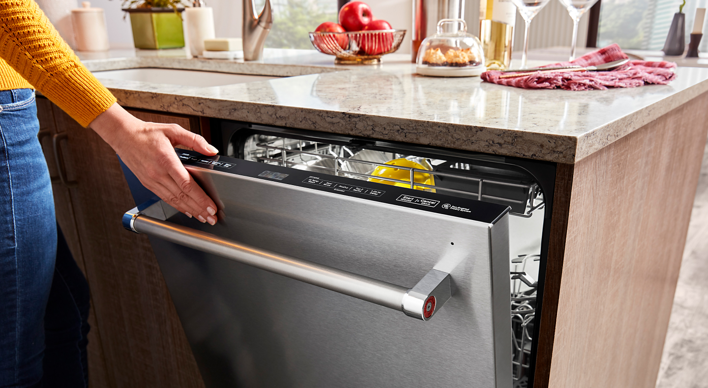 Person closing a stainless steel top control dishwasher