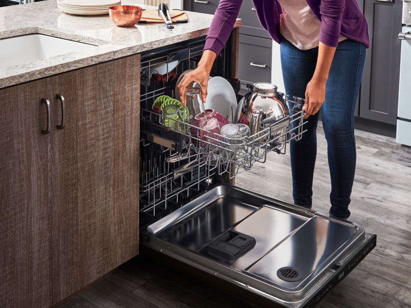 Woman loading dishes into a three rack dishwasher