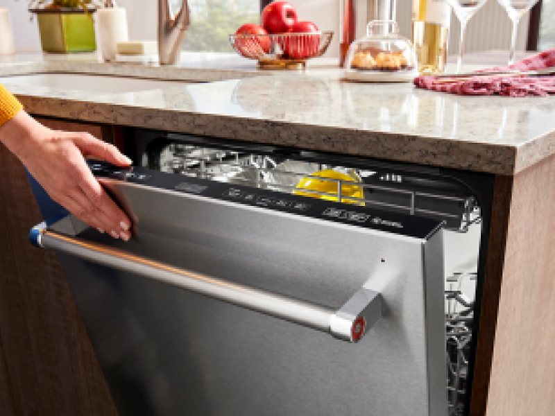 Person closing a stainless steel top control dishwasher
