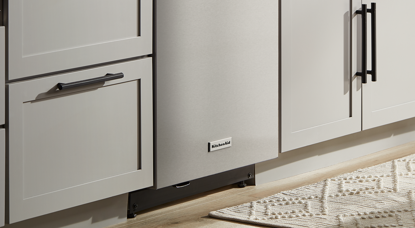 Stainless steel KitchenAid® dishwasher in between light grey cabinets