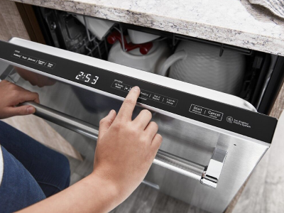 A closeup of a person programming a stainless steel KitchenAid® dishwasher.