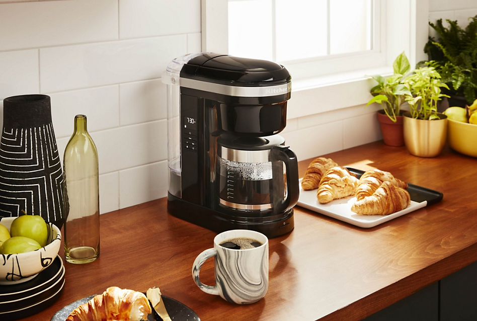 KitchenAid® auto drip coffee maker on counter with coffee and croissants